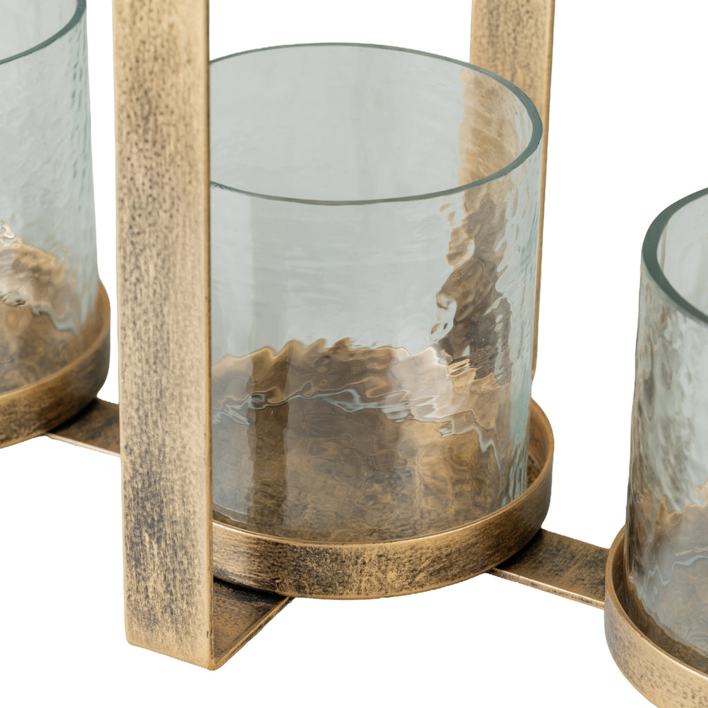 Close-up of a hammered-glass holder resting in its mottled gold-toned circular base beside the metal frame.