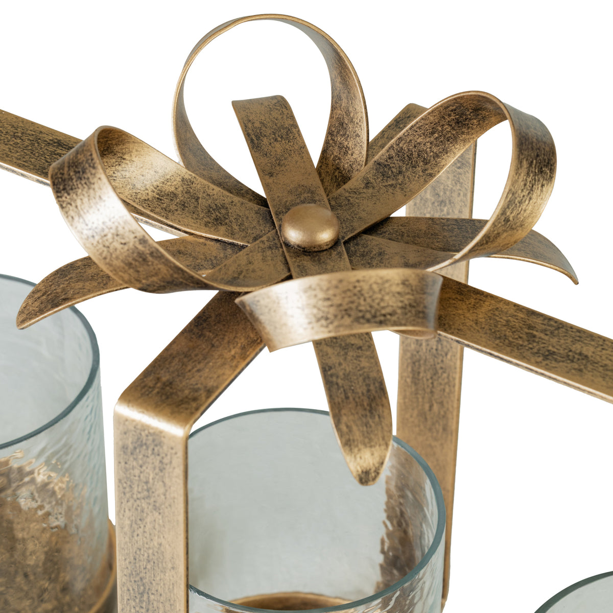 Detail of the looping metal bow and curved ribbon tails with an aged-gold finish above the glass holders.