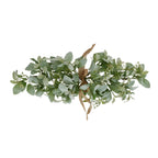 Sage-green artificial foliage bouquet laid horizontally on white, with a tan bow at the centre and tiny white flower or bud details among the leaves.