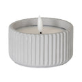 Small LED candle with pale grey ribbed sides, a recessed pale top and a white flame-shaped centre against a white background.