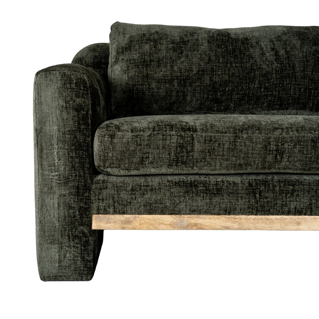 Close view of one front corner of the sofa, showing the broad arm, seat and back cushion beside the pale brown rail.