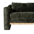 Close view of one front corner of the sofa, showing the broad arm, seat and back cushion beside the pale brown rail.
