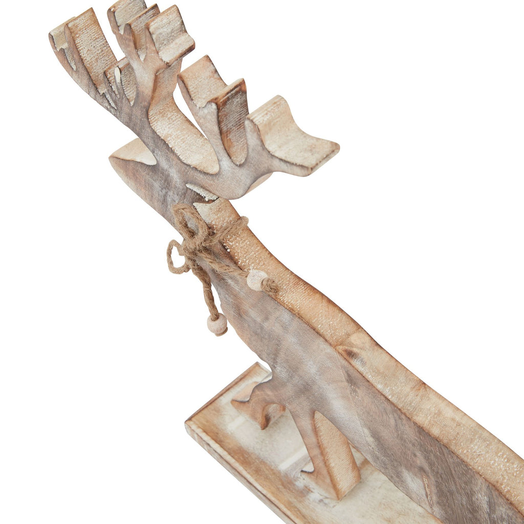 Angled detail of the stag ornament showing the pale edges of its antlers and body, neck bow and part of the rectangular base.