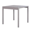 Grey dining table seen at an angle, with a broad slatted top, thick frame and four straight square legs.