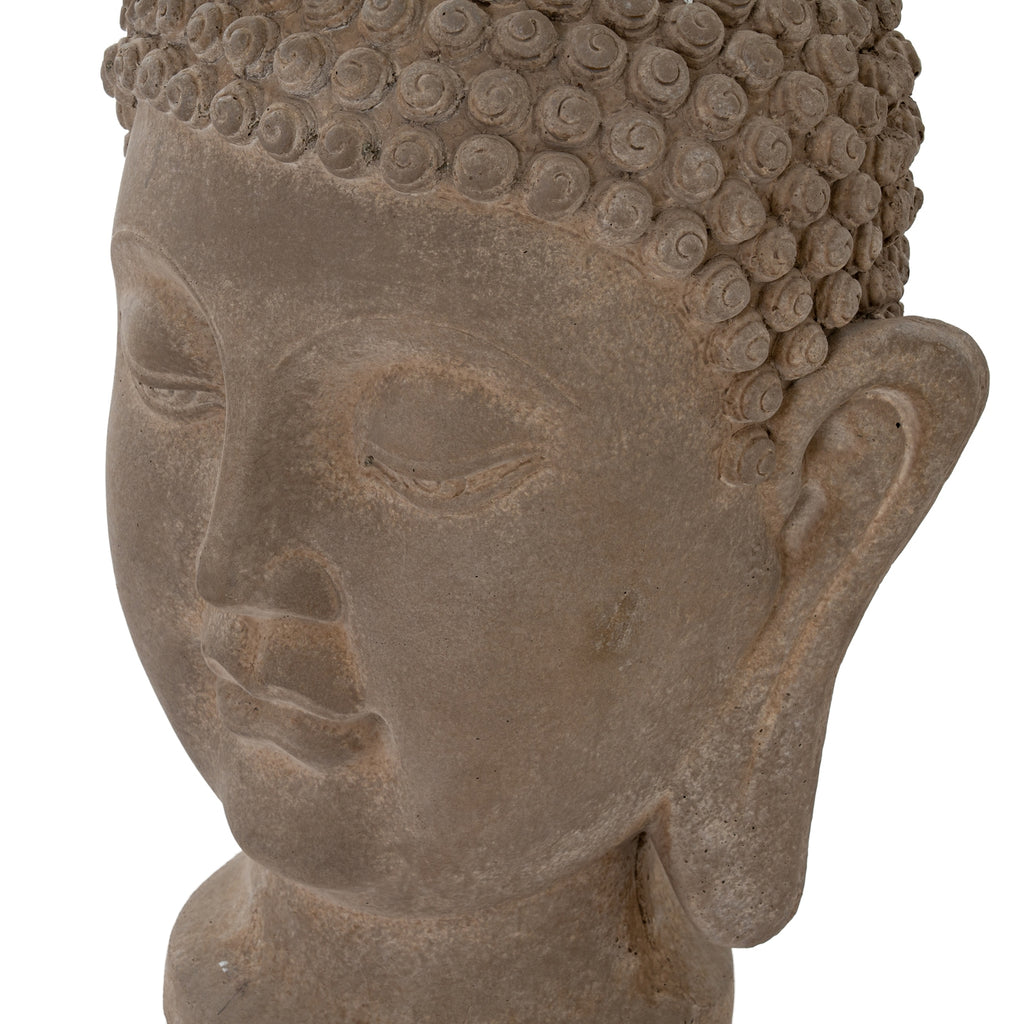 Close-up of the Buddha head's closed eyes, cheek and long ear, showing the mottled brown surface and raised curls along the hairline.