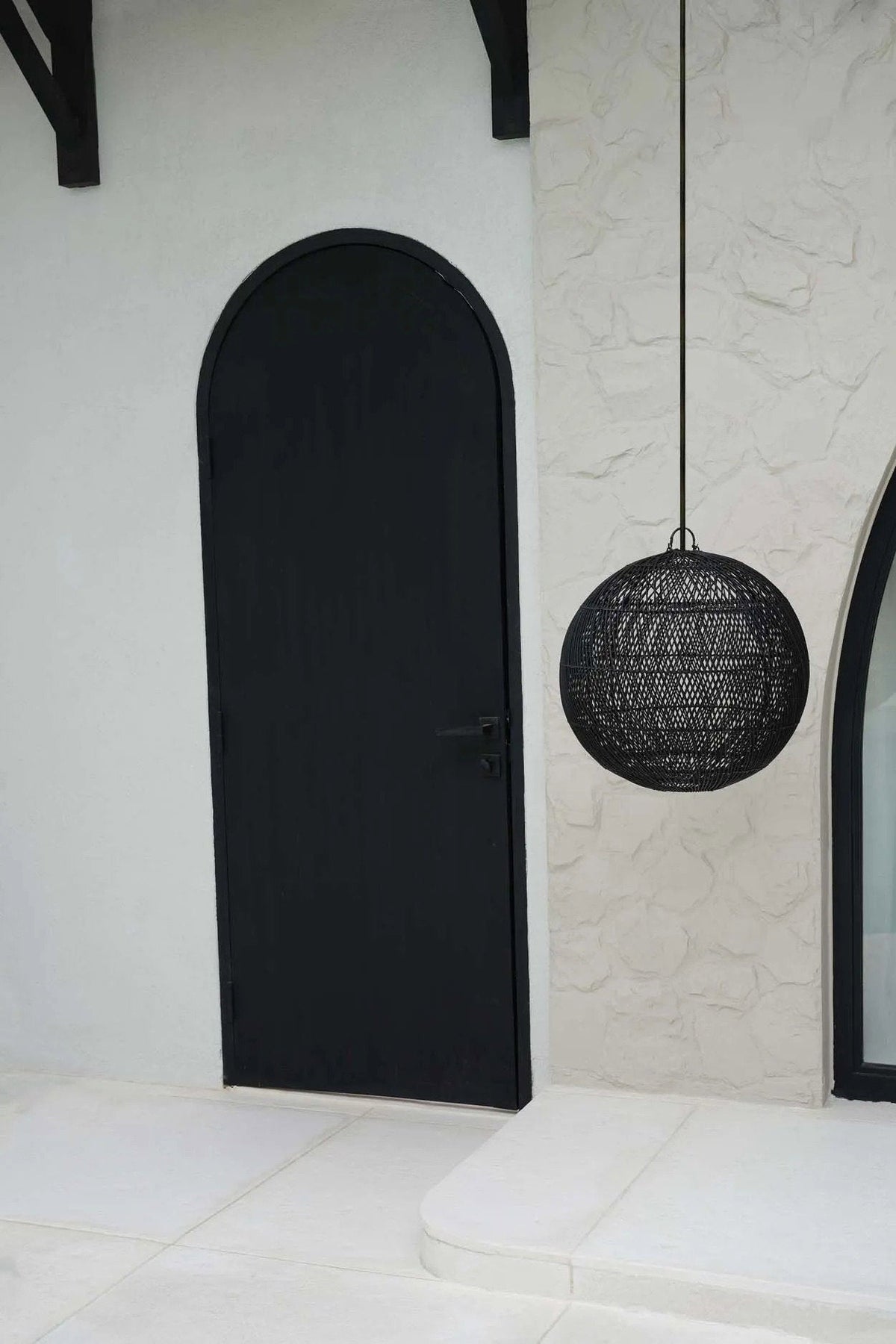 Bubble Rattan Pendant Light – Black, Medium – suspended beside a black arched doorway