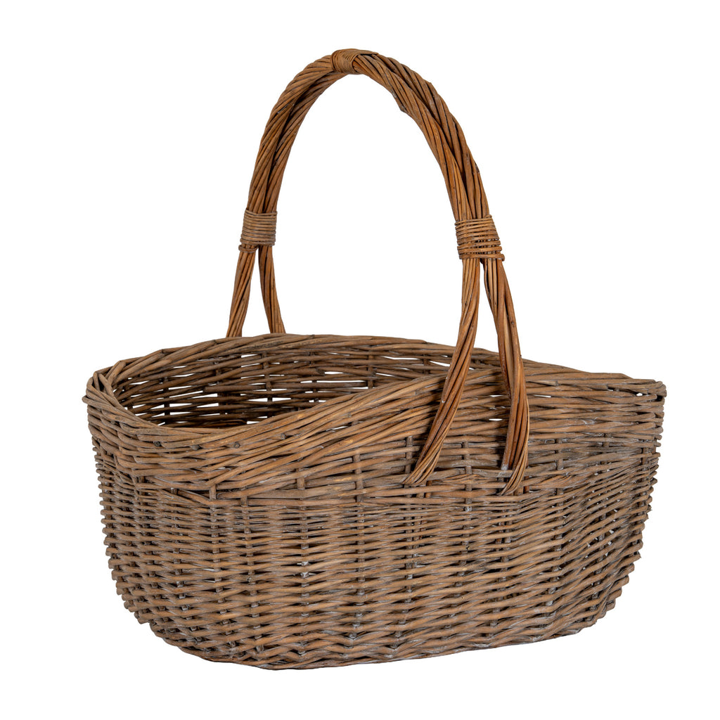 Angled view of a brown woven trug basket with an open oval body and a tall bundled handle bound at the crown and sides.