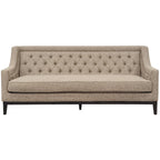 Front view of a taupe sofa with a diamond-buttoned back, long piped seat cushion and dark wooden base.
