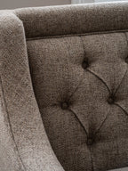 Close-up of the sofa's taupe and beige woven fabric, deep buttoning and piping beside the arm.