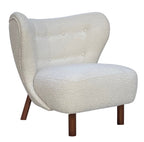 Front three-quarter view of the cream bouclé chair showing the curved buttoned back, piped edges and stained wooden legs.