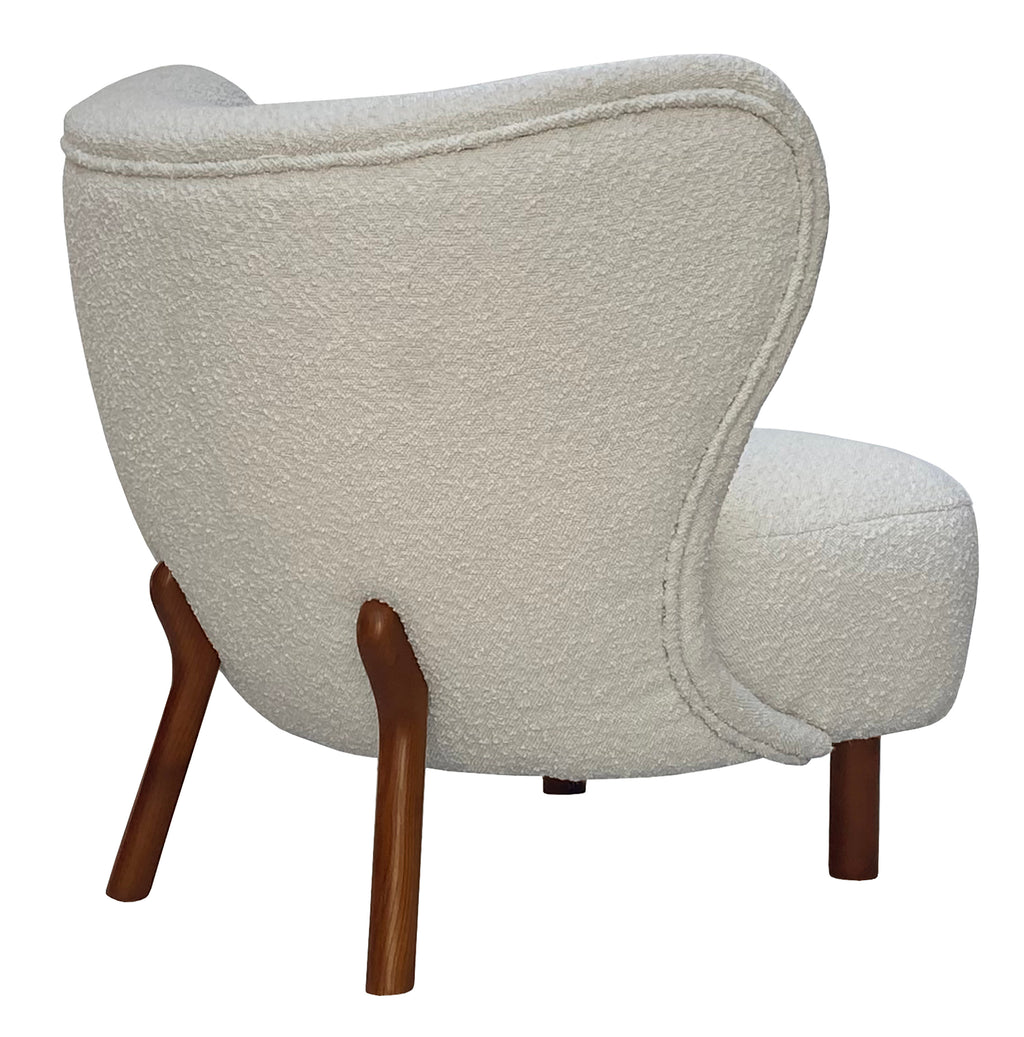 Rear three-quarter view of the cream chair showing the upholstered back, curved piping and angled brown wooden rear legs.