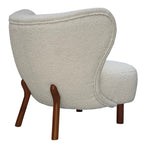 Rear three-quarter view of the cream chair showing the upholstered back, curved piping and angled brown wooden rear legs.