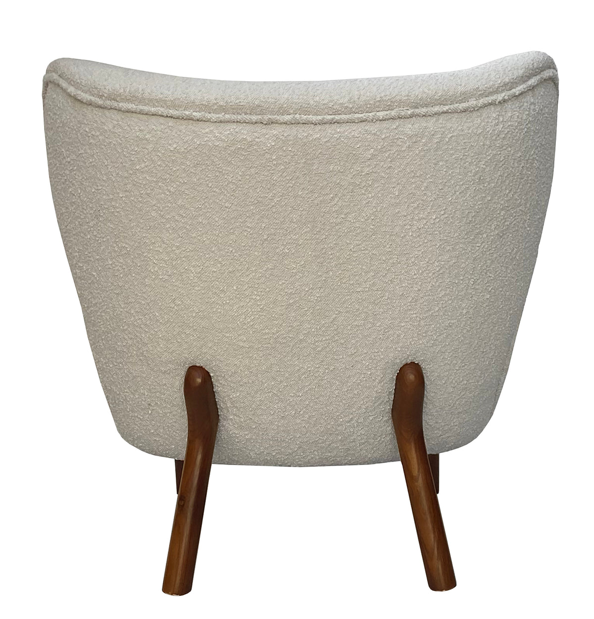 Straight rear view of the cream bouclé chair with a broad curved back, piping along the top and two splayed wooden legs.