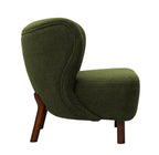 Side view of the green bouclé chair showing the curved back, piped upholstery and angled wooden rear leg.