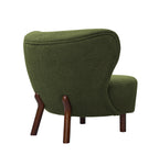 Rear three-quarter view of the green bouclé chair with piping around the back and wooden legs extending up its rear.