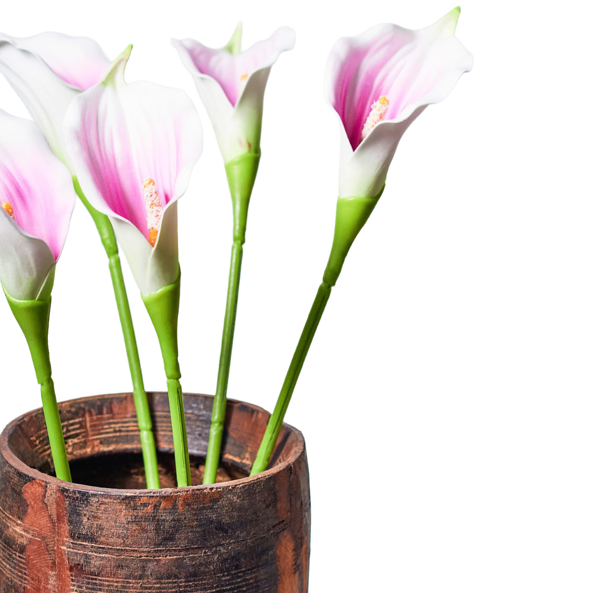 Close-up of cream-white and lilac-pink faux calla lilies on green stems in a brown vessel with visible grain, against a white background.