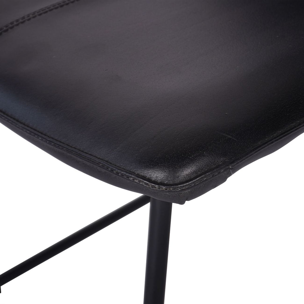 Close-up of the rounded leather seat corner and stitched border above the black tubular frame.