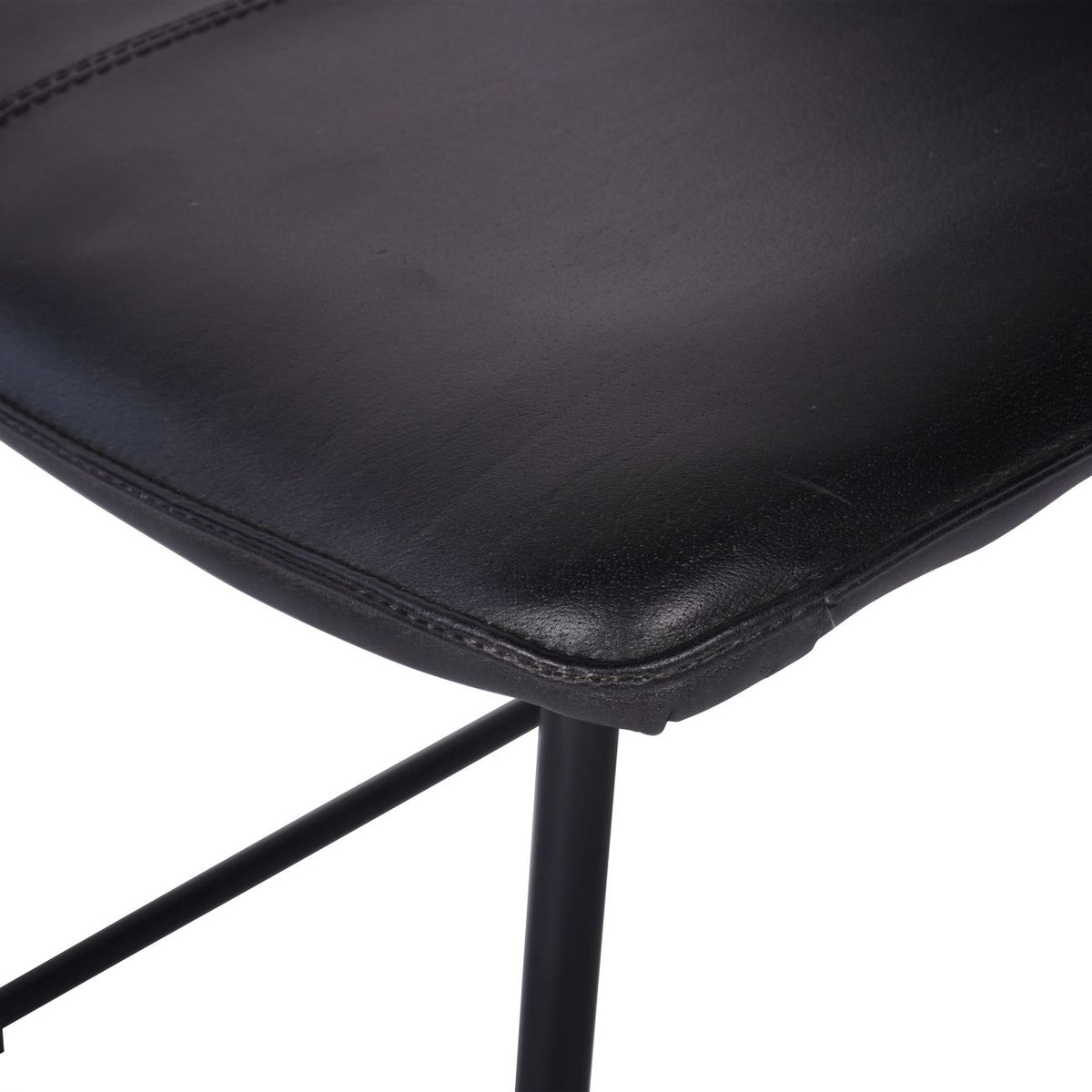 Close-up of the rounded leather seat corner and stitched border above the black tubular frame.