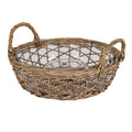 Angled view of an empty transparent round dish with a central circular well, sitting in a brown open-lattice carrier with two loop handles and a densely woven base.