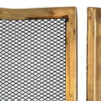 Close-up of black diamond mesh beside the brass-tone panel edges, showing darker markings and surface texture on the frame.
