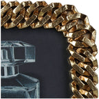 Close-up of the photo frame's upper corner showing textured gold chain links and dark recesses.