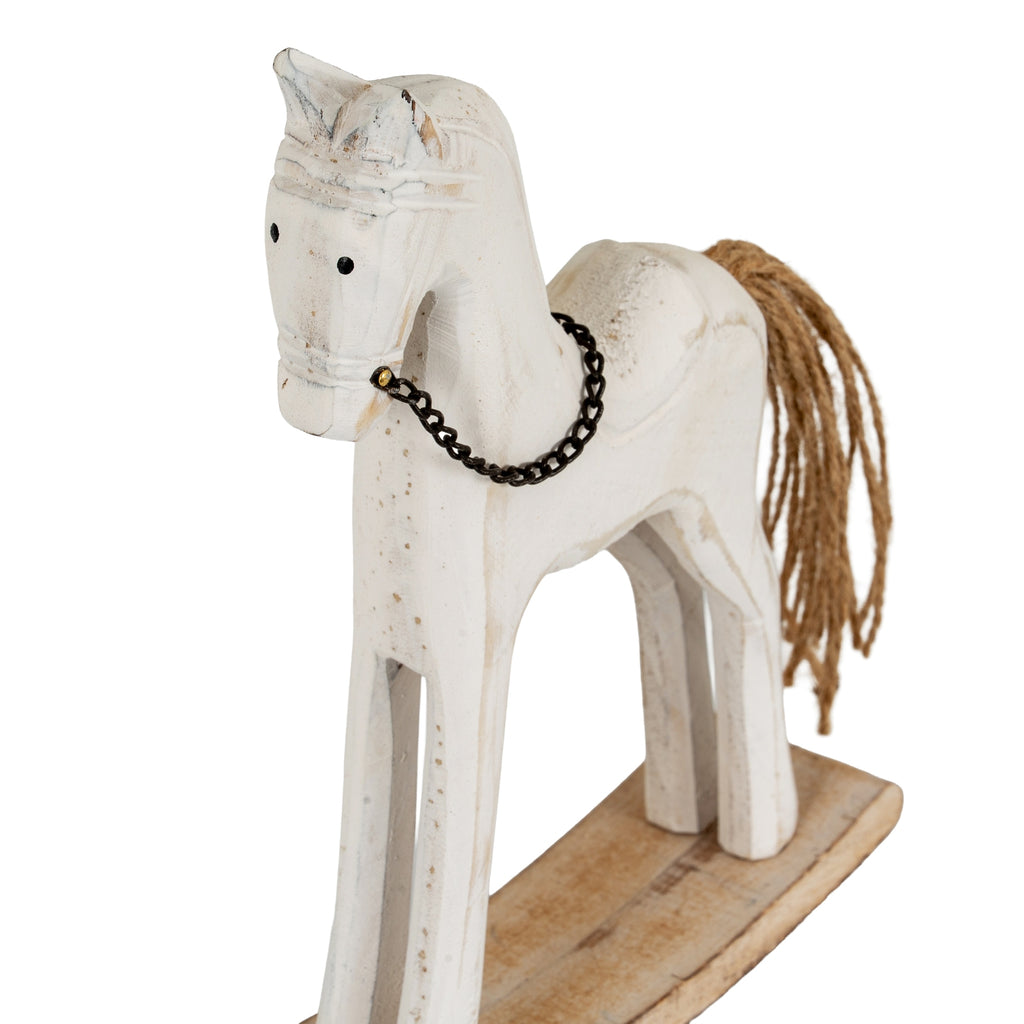 Close angled view of the horse's face and neck, showing black dot eyes, a dark chain bridle and worn-looking whitewashed detail.