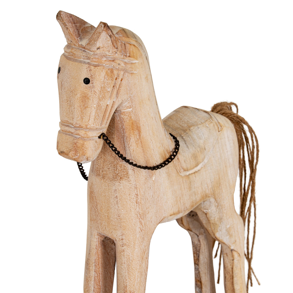 Close view of the rocking horse's pointed ears, dark eyes and pale textured face, with the chain bridle draped across its neck.