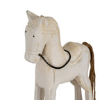 Close-up of the rocking horse’s head and body, showing black dot eyes, outlined mane, worn-looking whitewash and dark chain bridle.