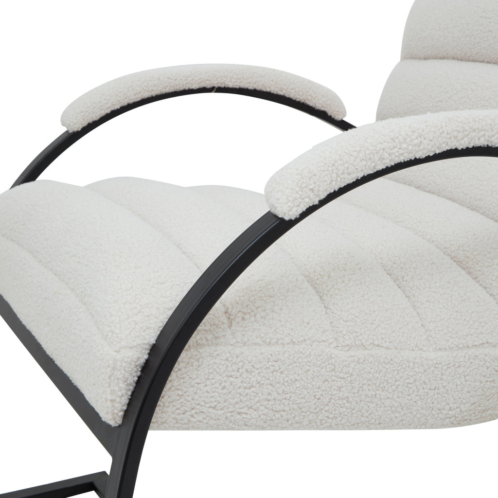 Close view of the pale looped upholstery across the channelled seat and arm caps, with black curved arm supports.