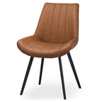Front three-quarter view of the tan dining chair, showing vertical channel seams, curved seat sides and four black splayed legs on a white background.