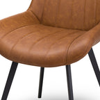 Close-up of the mottled tan seat and lower back, showing channel stitching, curved sides and seams around the front edge, with portions of the black legs below.