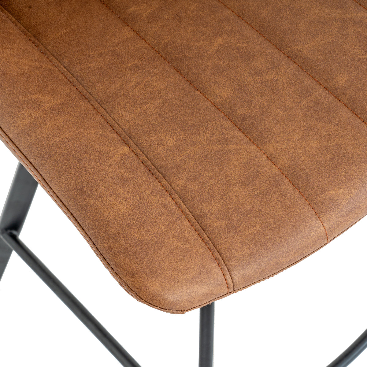 Close-up of the tan seat showing its mottled surface, stitched channels and rounded edge, with part of the black base below.