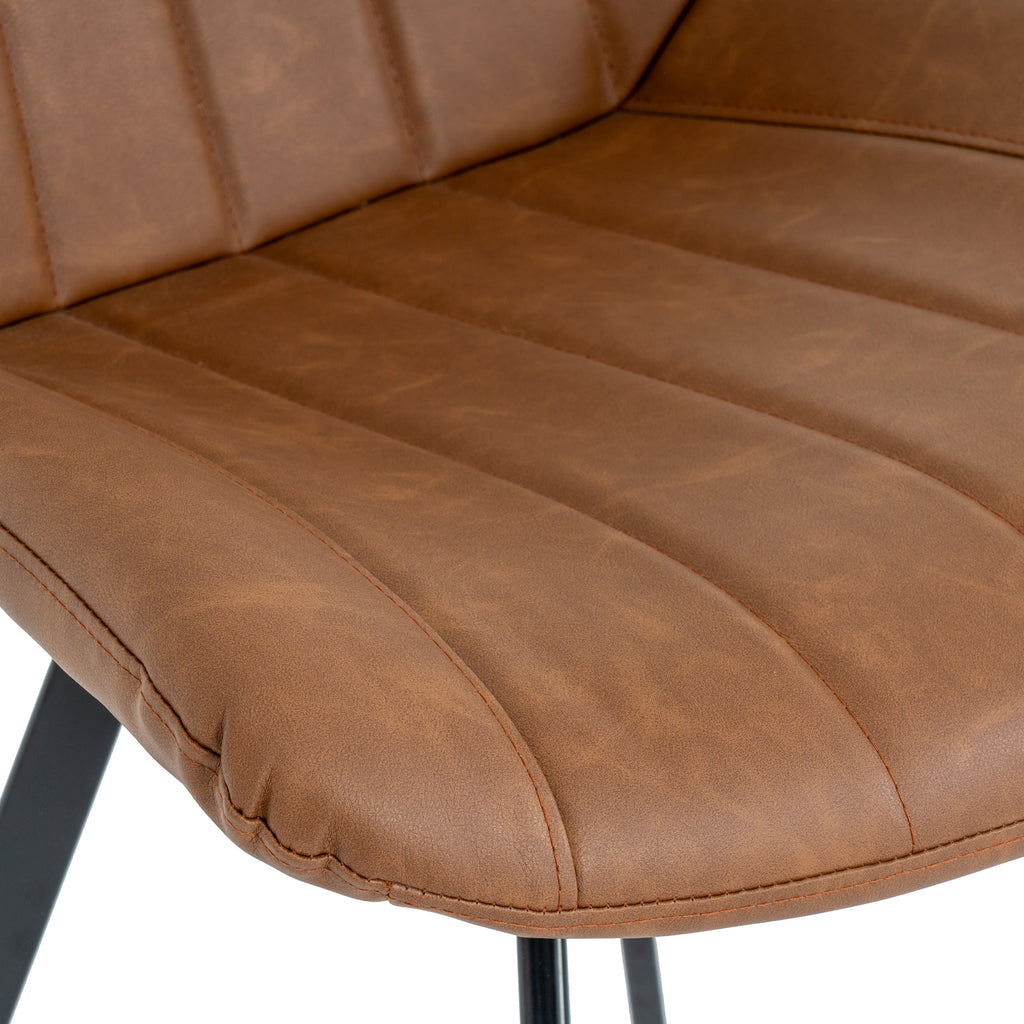 Close-up of the tan chair seat showing mottled surface detail, stitched channels and seams around the curved front edge.