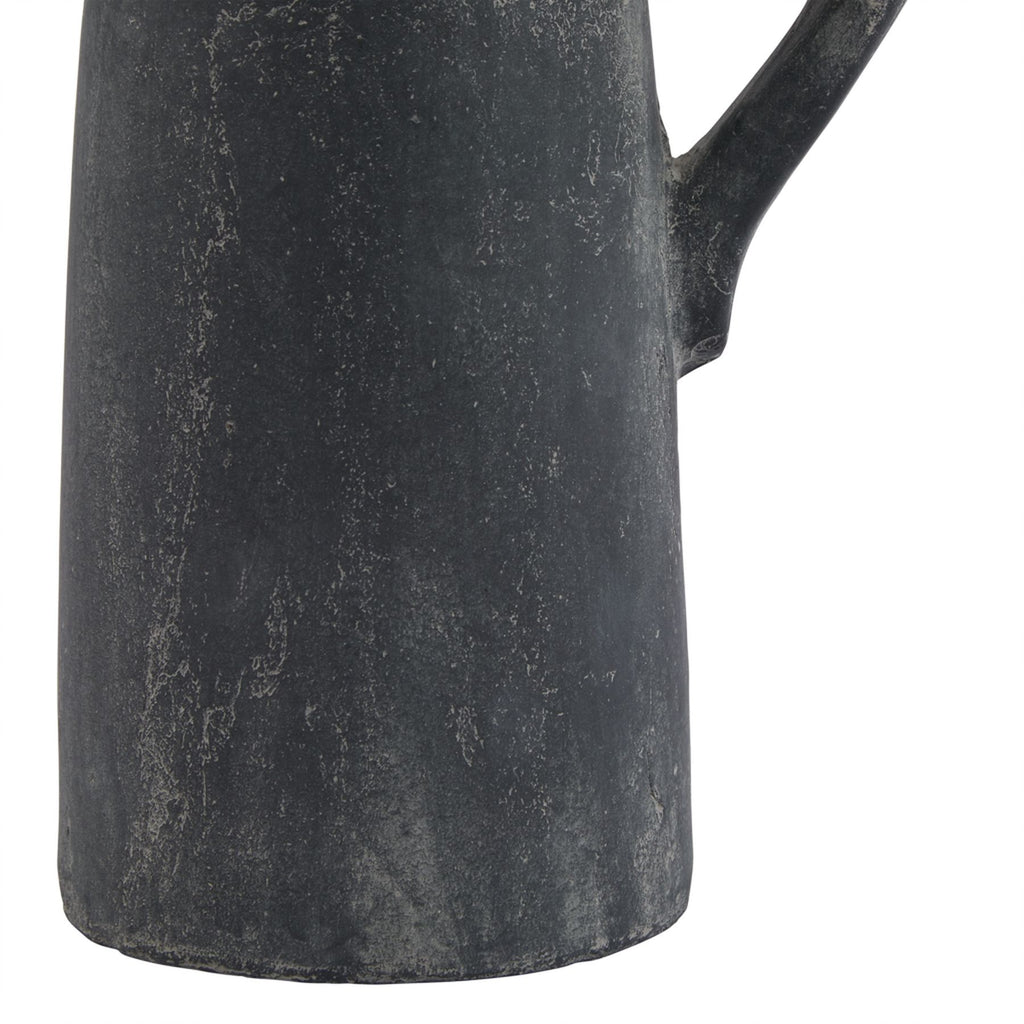 Detail of the jug's lower charcoal-grey body and rounded base edge, with fine pale irregular lines and the lower handle attachment visible.