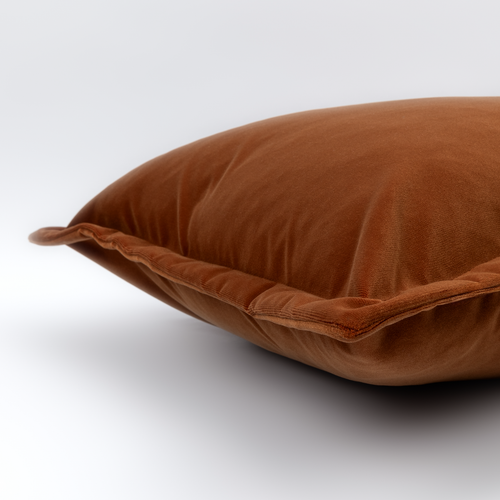 Angled close-up of the rust velvet Ciro Lumbar Cushion with its piped edge