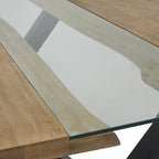 Detail of the transparent central panel with irregular grain-patterned edges visible beneath it and a dark edge across the end of the tabletop.