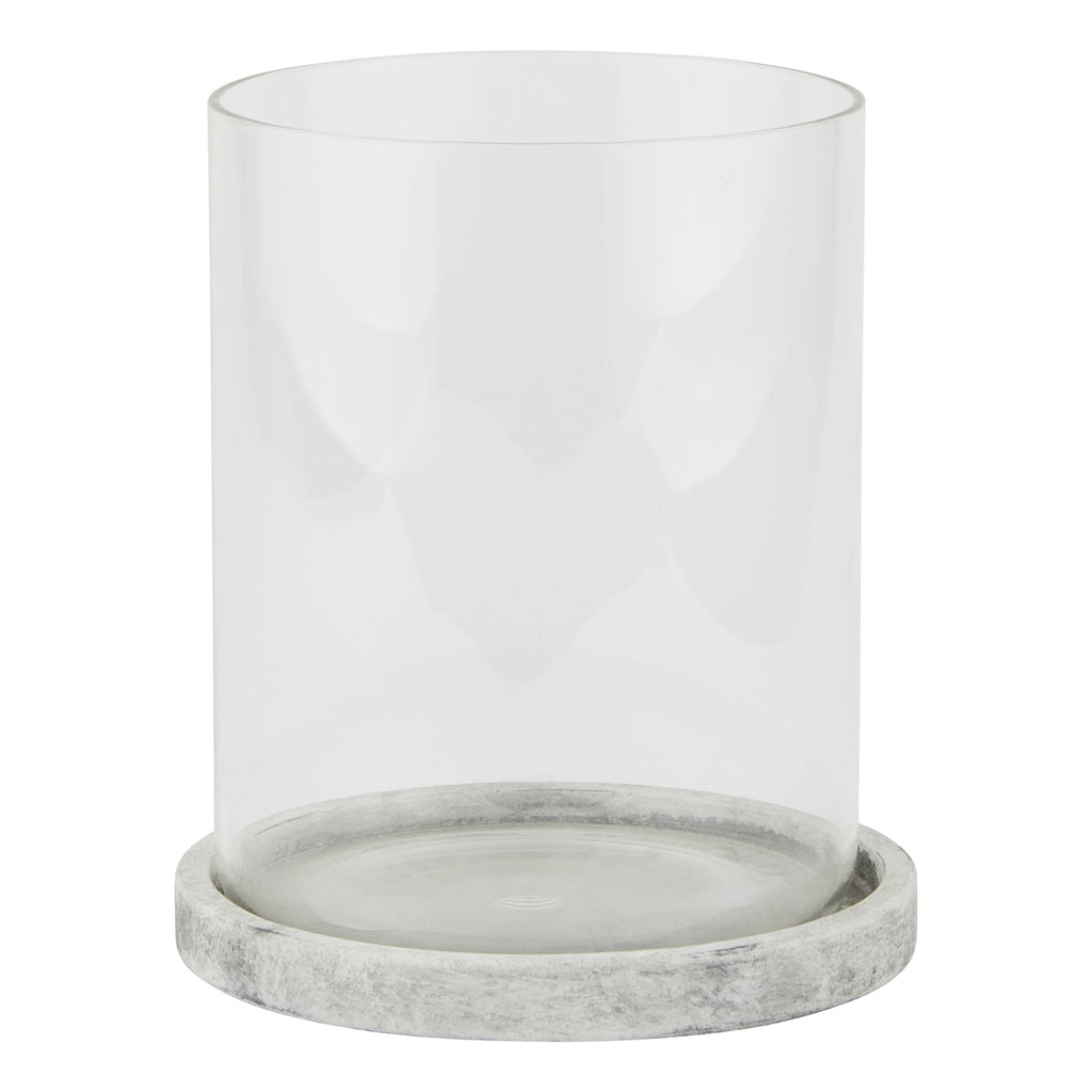 Front view of a clear cylindrical candle lantern on a shallow pale grey round base with mottled markings.