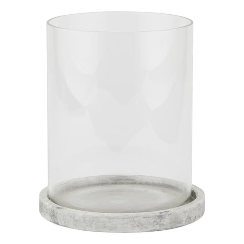 Front view of a clear cylindrical candle lantern on a shallow pale grey round base with mottled markings.