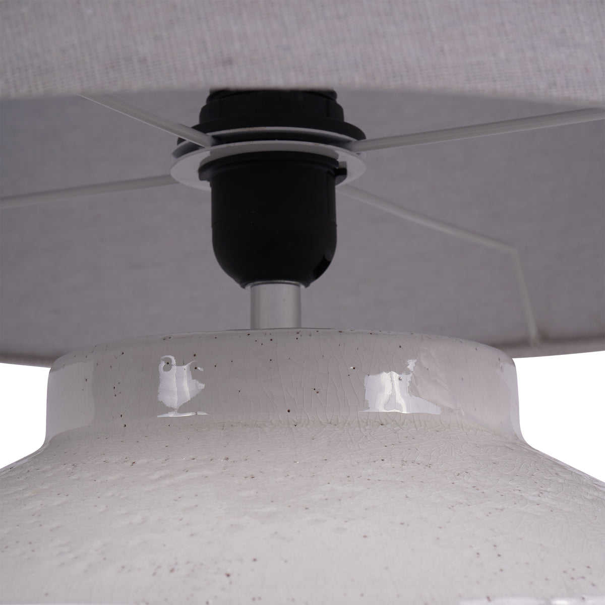 Close-up beneath the shade showing the dark lampholder, internal supports and crackled white glaze on the base neck and shoulder.