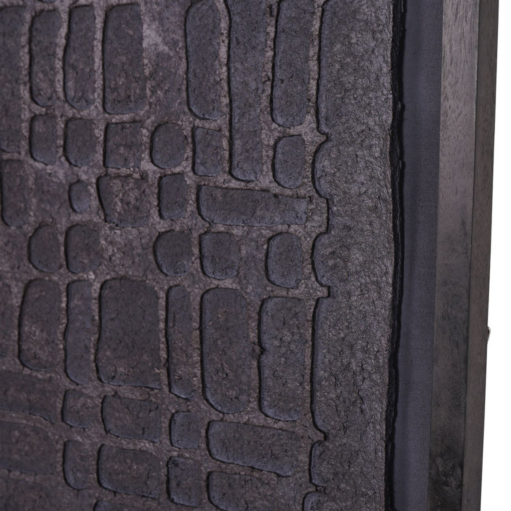 Close-up of irregular embossed blocks, the rough panel edge and distressed black frame.