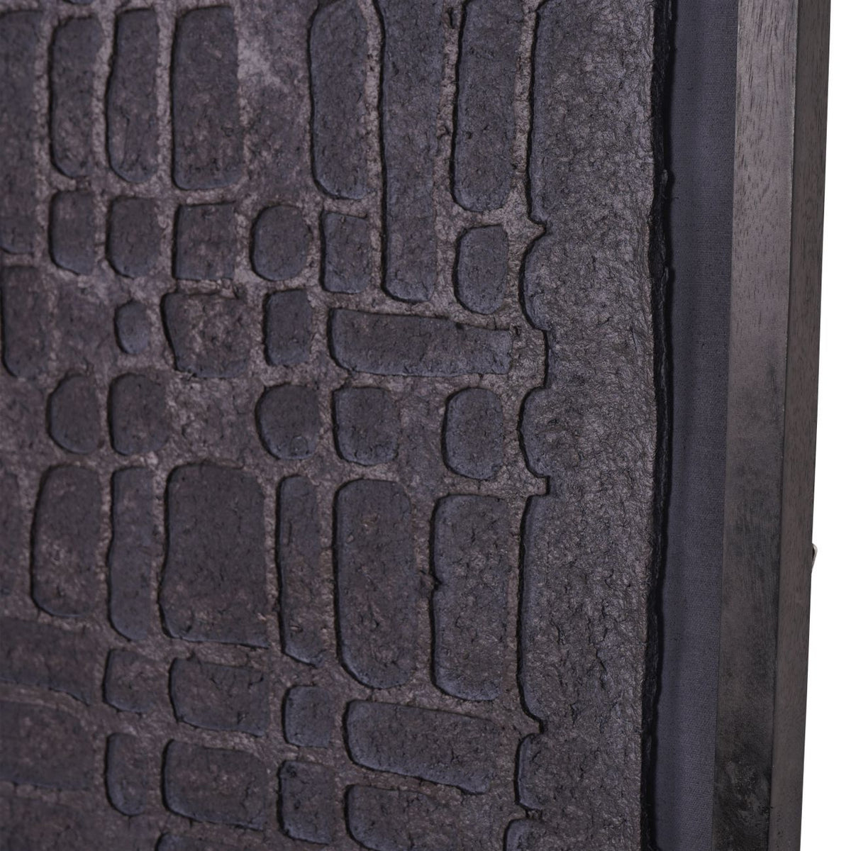 Close-up of irregular embossed blocks, the rough panel edge and distressed black frame.