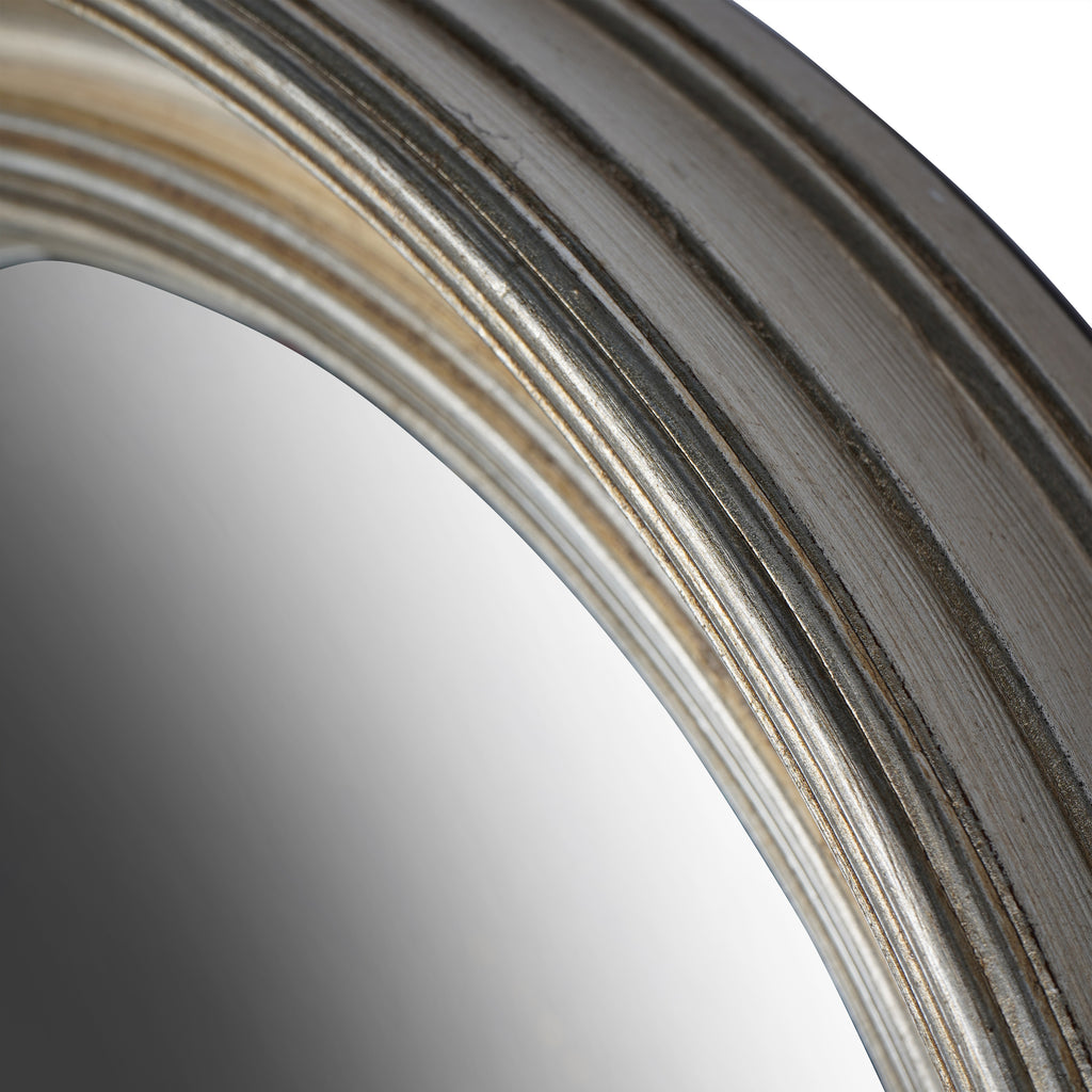 Close-up along the curved frame edge showing silver highlights, dark grooves and fine surface texture beside the glass.
