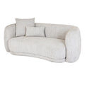 Angled front view of a pale cream curved sofa with a broad seat cushion and square and rectangular cushions arranged at one end.