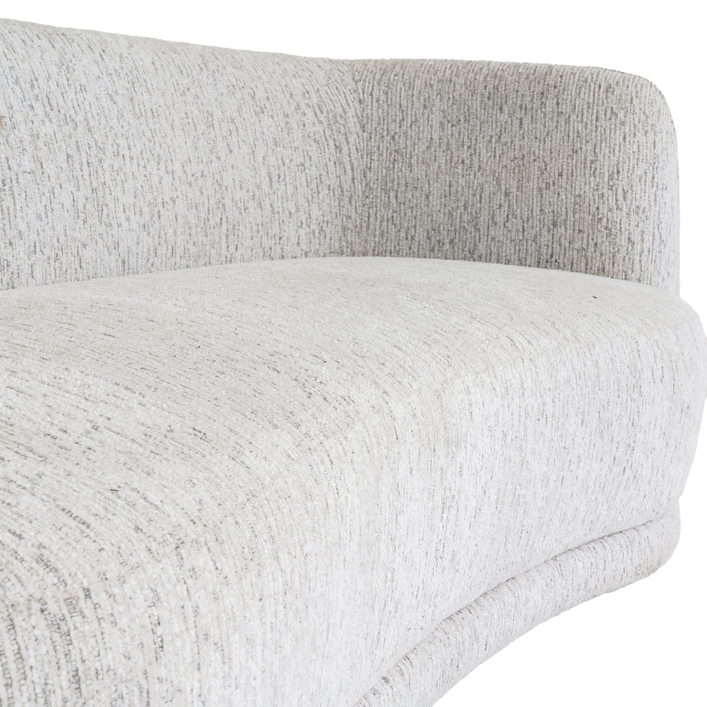 Close-up of the sofa's seat cushion and curved back, showing narrow lines and darker flecks in the pale cream surface.