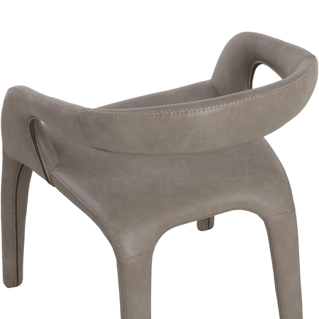 Close rear view of the taupe chair, showing cross-stitching along the curved back and arms, tonal variation in the faux leather and the seat below.