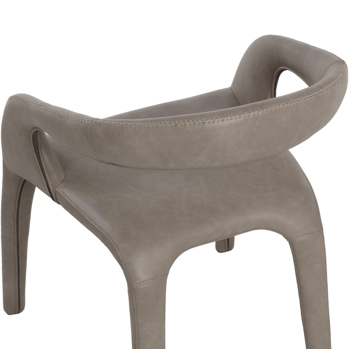 Close rear view of the taupe chair, showing cross-stitching along the curved back and arms, tonal variation in the faux leather and the seat below.