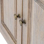 Close-up of two rounded brass-coloured knobs on adjoining panelled doors, against the streaked tan-grey finish.