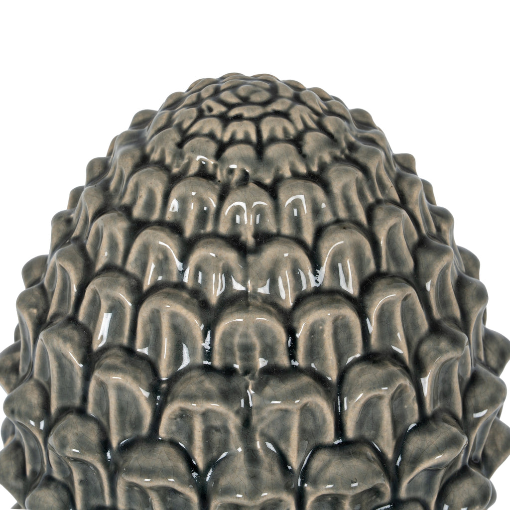 Close-up of the acorn crown showing overlapping rounded scales, dark recesses and light reflecting from the glossy crackle finish.