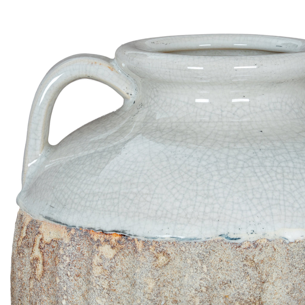 Close-up of a curved shoulder handle and the uneven edge where the pale crackle glaze meets the rough brown finish.