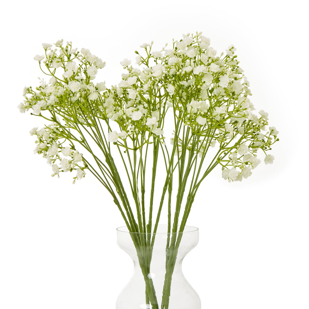 Several cream artificial gypsophila stems arranged in a clear waisted vase, forming a broad spray of small flowers against a white background.